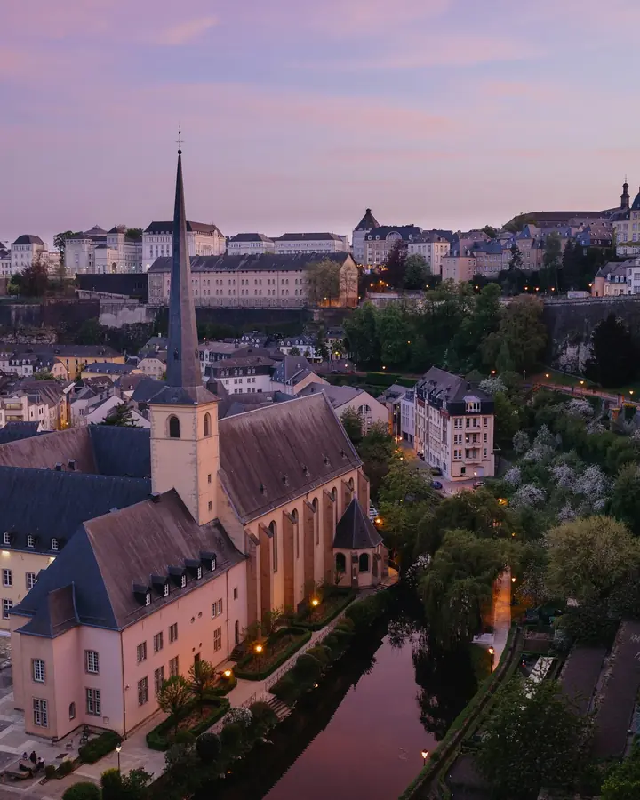 View of Luxembourg City at dusk, with the Grund district and Neumünster Abbey